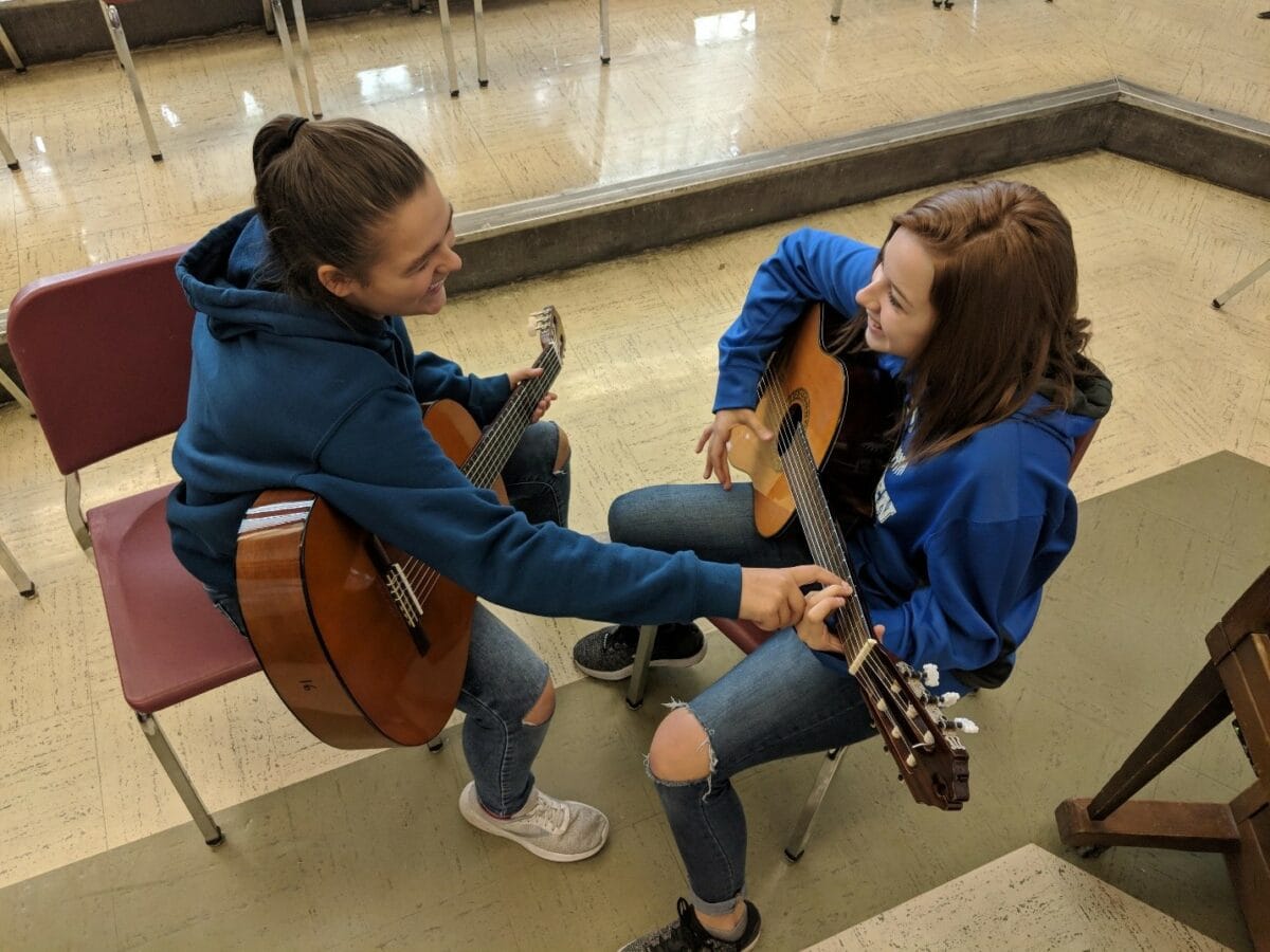 students helping each other during guitar class