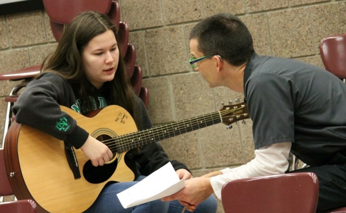 guitar teacher with student holding guitar