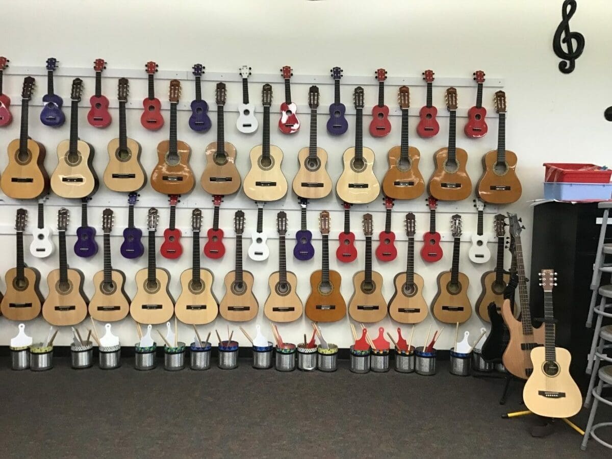 guitars and ukuleles stored hanging on classroom wall