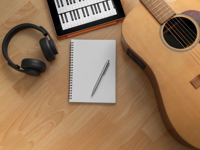 song writing with guitar headphones notebook tablet