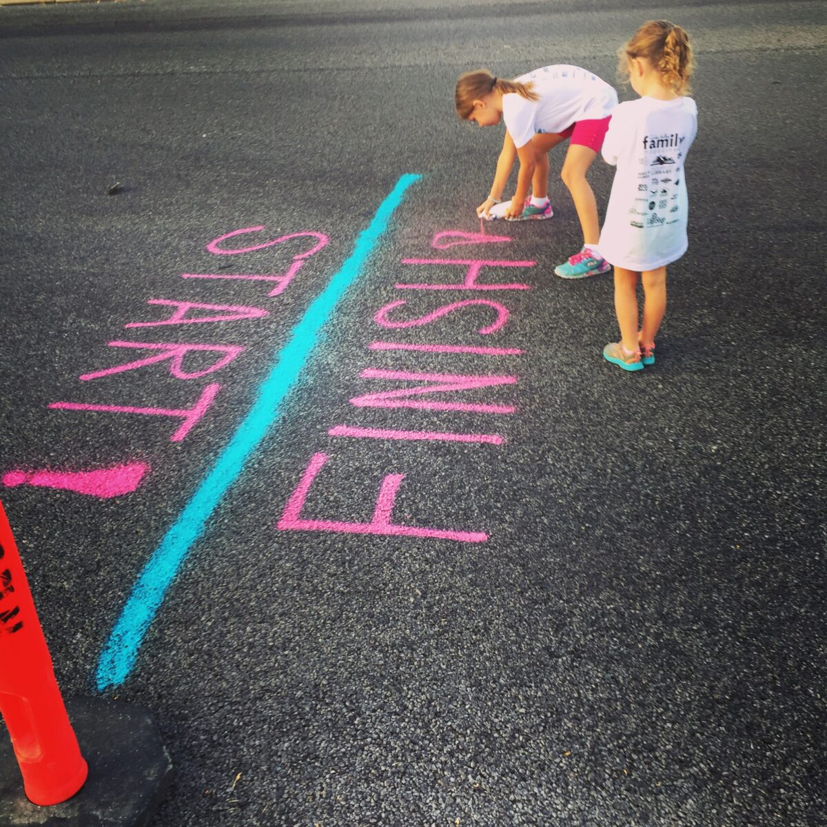 two girls spraying start and finish line on the ground