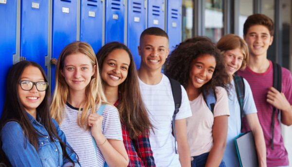 Teenage School Kids Smiling To Camera In School Corridor