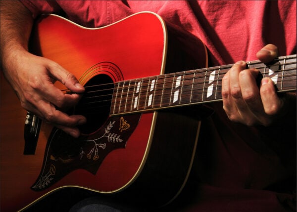close up photo of an guitarist playing an acoustic guitar