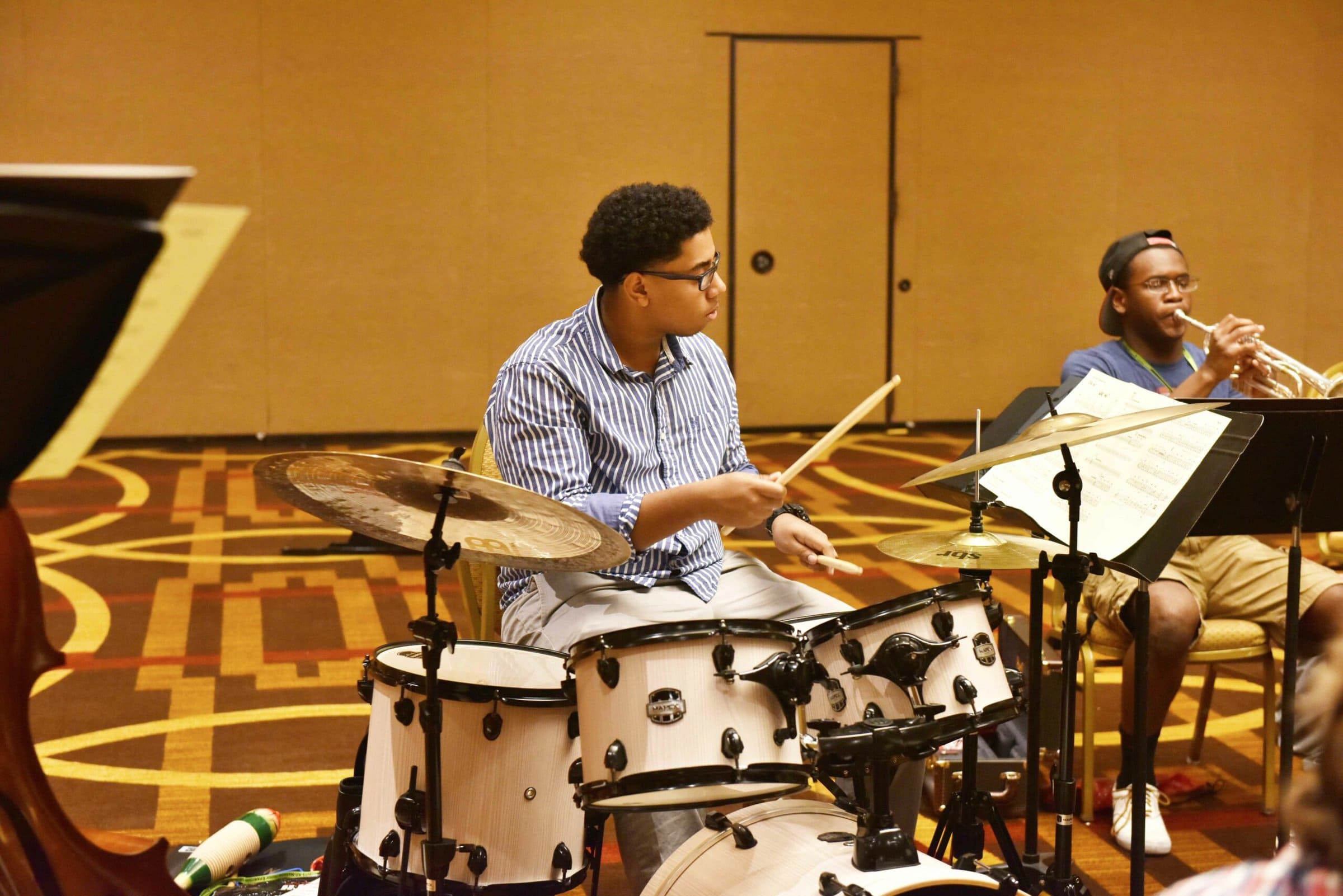 Student playing drums on the drum set looking at sheet music.