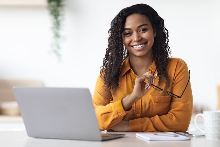 woman at desk smiling holding glasses