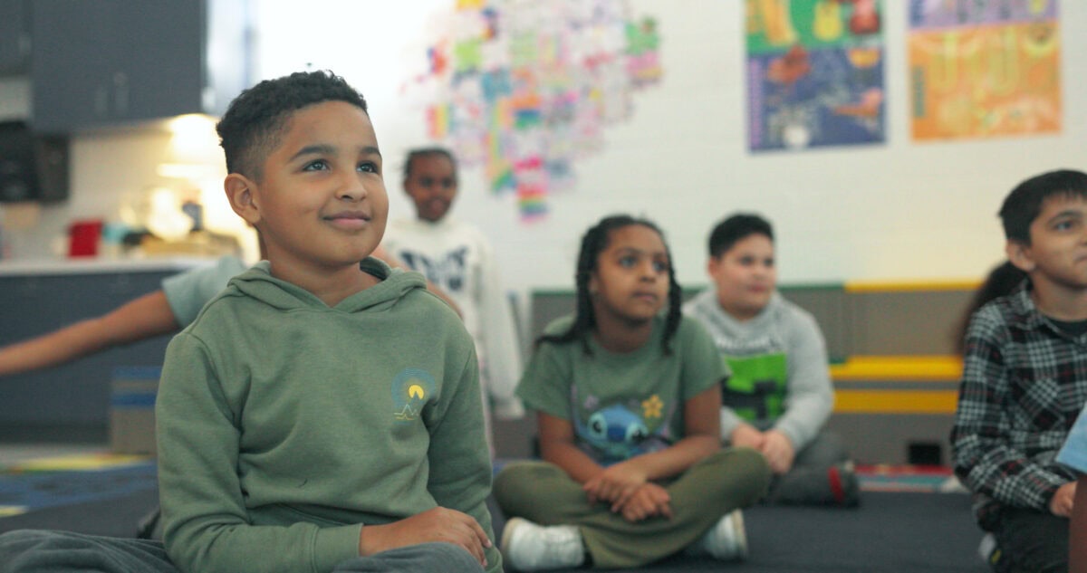 students smiling, sitting and listening in music class