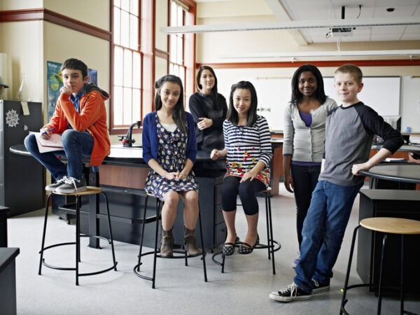 Group of young students with teacher looking at camera in classroom