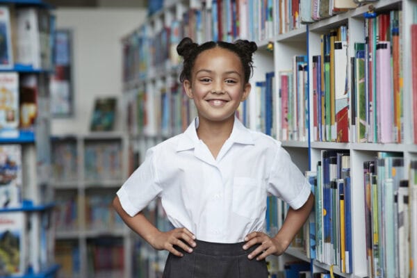confident smiling young girl with hands on her hips in the library