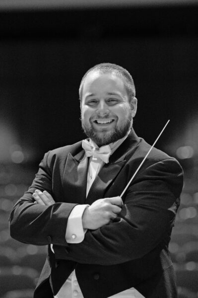 Christopher Brandt headshot in tuxedo and holding conductor's baton