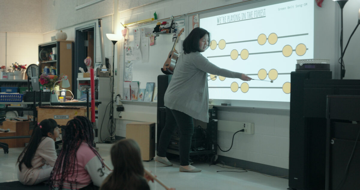 elementary music educator at smartboard in front of students in classroom