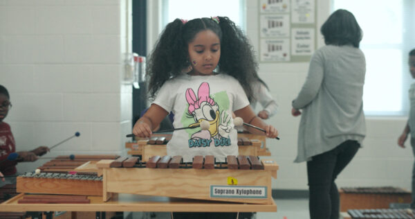elementary student in classroom practicing music on xylophone