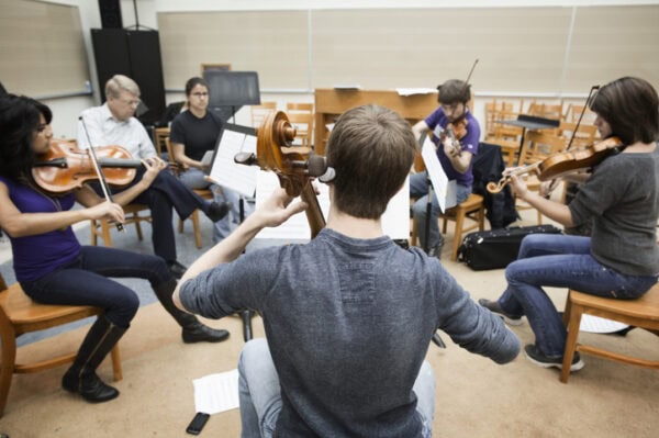 Strings musicians performing together in classroom