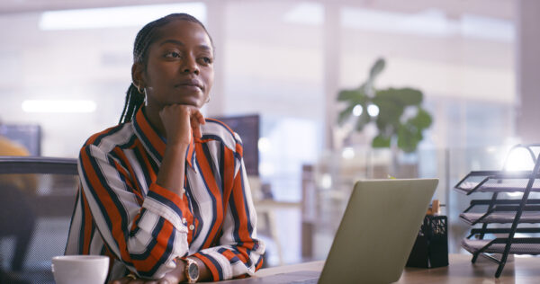 Woman sitting at desk with laptop engaging in self-reflection