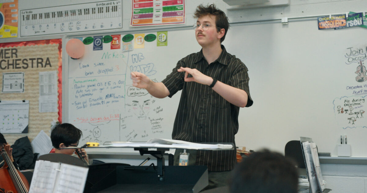 orchestra director in classroom rehearsal