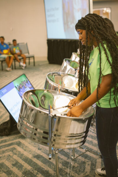 student in green shirt playing steel drums