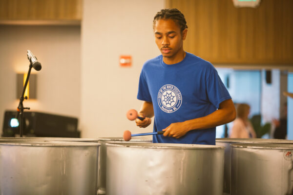 student in blue shirt playing steel drums