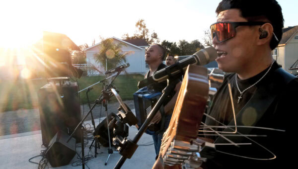 Young man singing performing in a latino band outdoors concert
