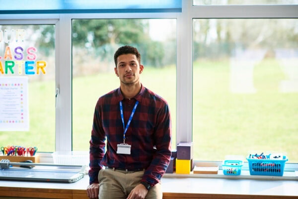 Portrait of male elementary school teacher in classroom facing camera