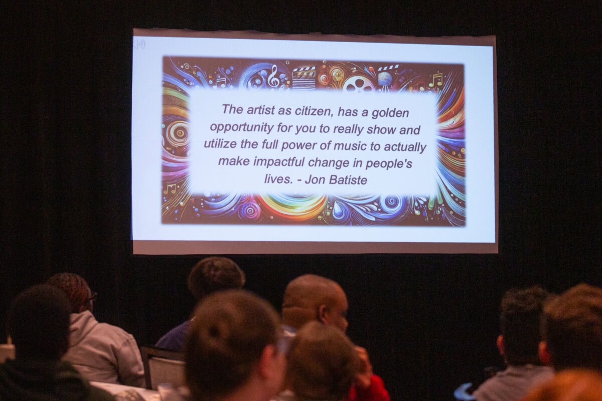 PowerPoint slide projected on screen at professional learning session with quote by Jon Batiste that says, The artist as citizen has a golden opportunity for you to really show and utilize the full power of music to actually make impactful change in people's lives.