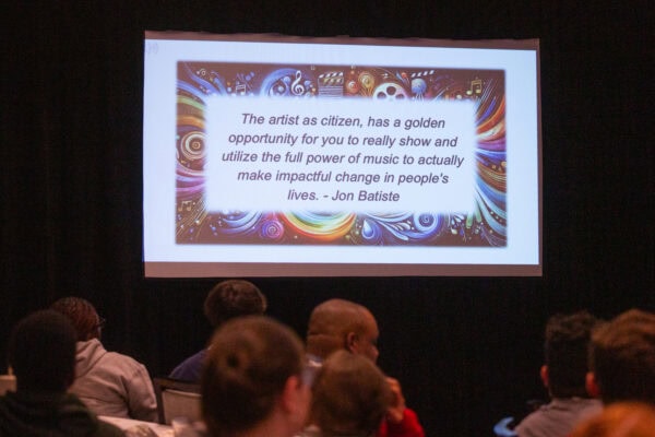 PowerPoint slide projected on screen at professional learning session with quote by Jon Batiste that says, The artist as citizen has a golden opportunity for you to really show and utilize the full power of music to actually make impactful change in people's lives.