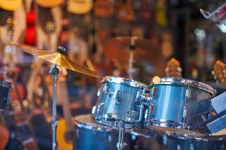 closeup of drumset with guitars in background