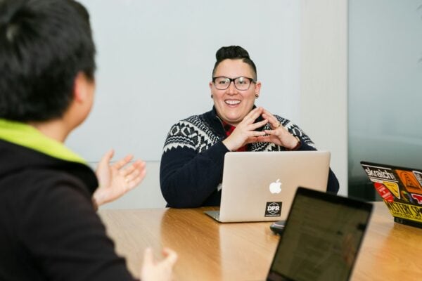 smiling colleagues in a meeting at shared table with laptops