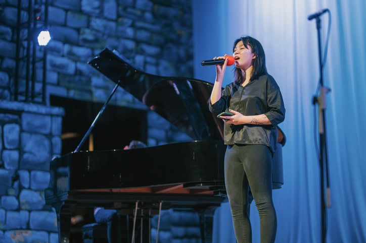 young Asian opera singer practicing solo on stage with pianist