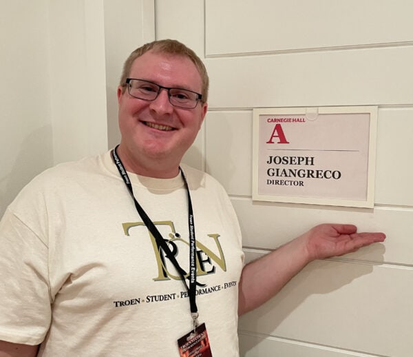 Joseph Giangreco standing beside Carnegie Hall sign with his name on it