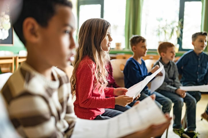 Middle school students practicing with sheet music in classroom