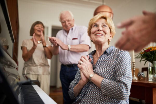 Senior people clapping hands for a friend playing piano