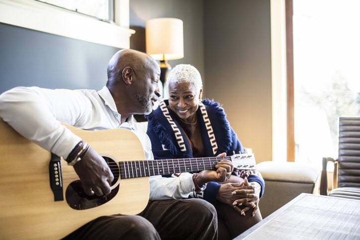 Senior man playing acoustic guitar for his wife