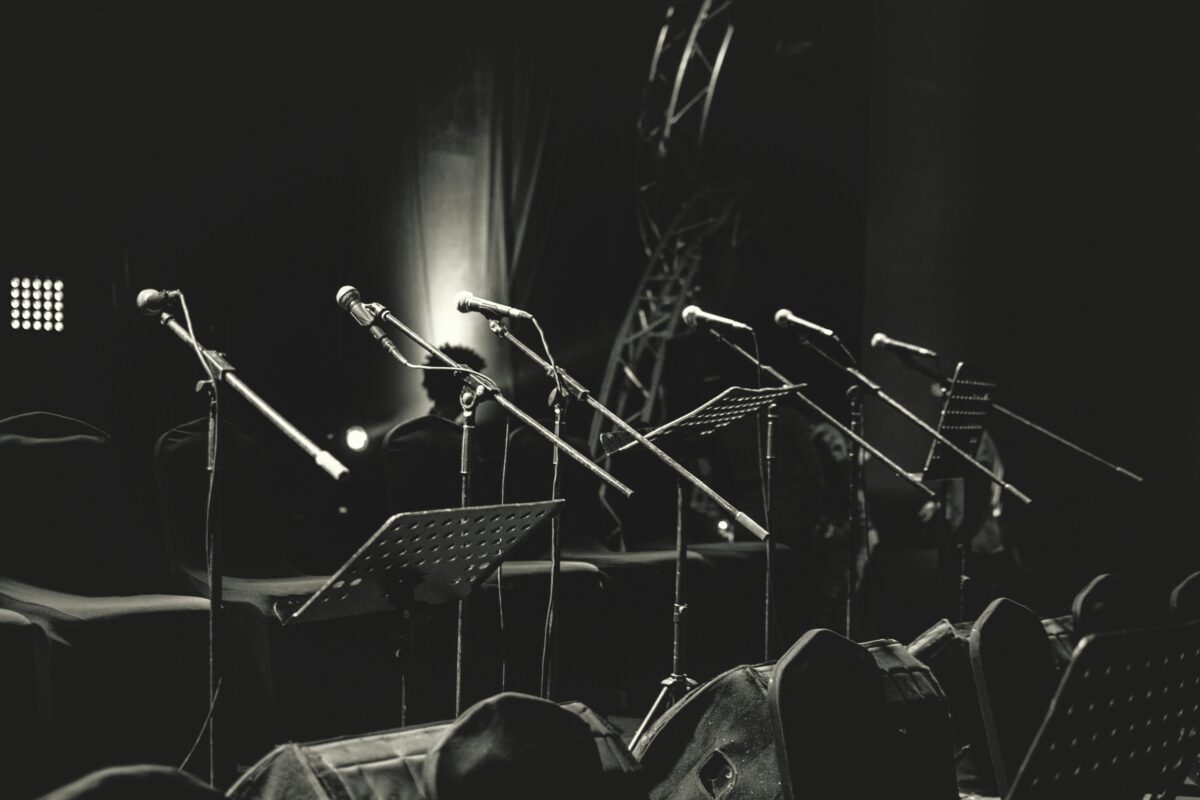 black and white photo of microphones and music stands on empty stage