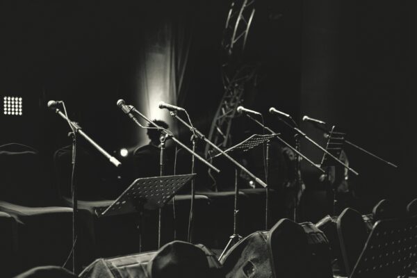 black and white photo of microphones and music stands on empty stage