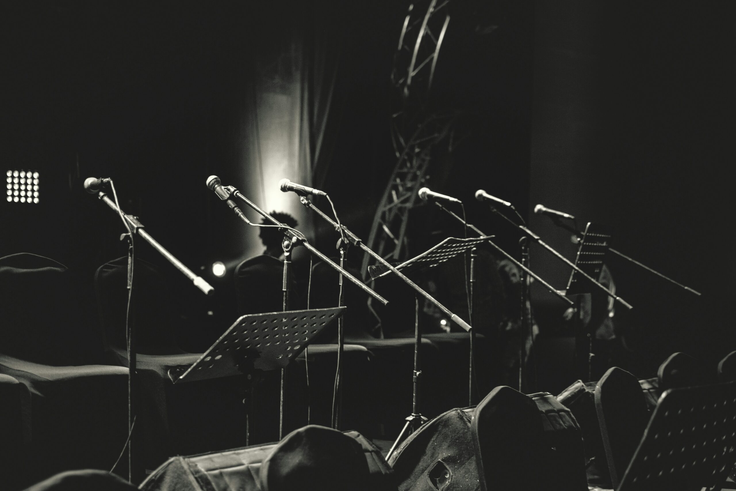 microphones and music stands on empty stage black and white photo of microphones and music stands on empty stage