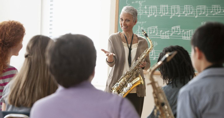 Students listening to older teacher in music class