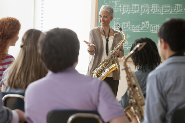 Students listening to older teacher in music class