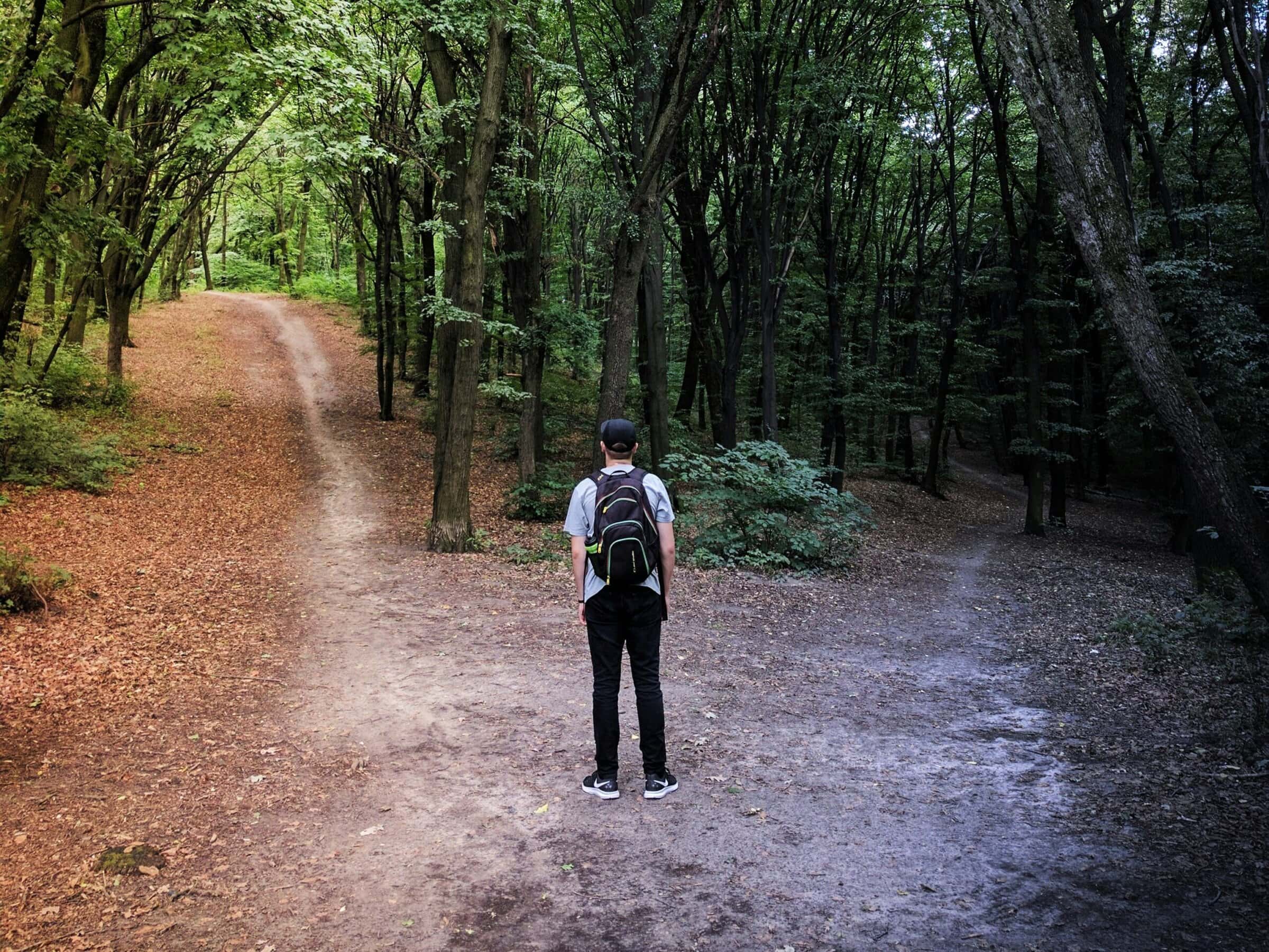 man standing in the trees at a crossroads