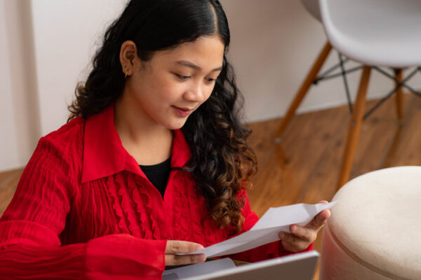 A young Southeast Asian student reading letter