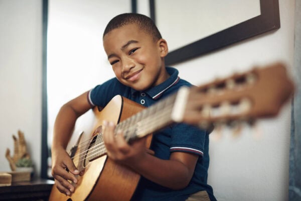 young smiling boy practicing guitar