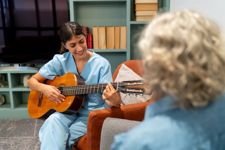 nurse playing guitar for patient