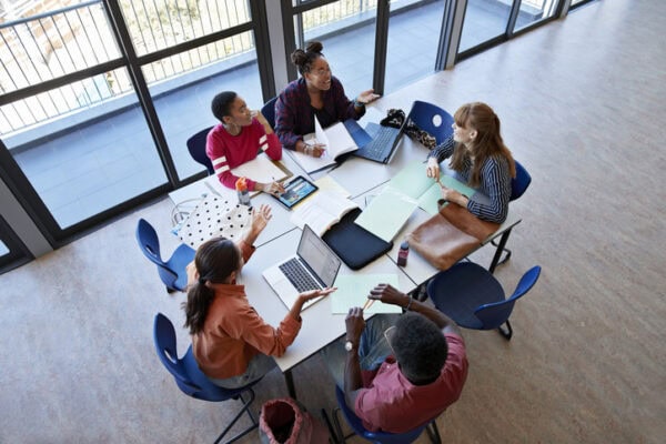 Cheerful students discussing at desk in classroom