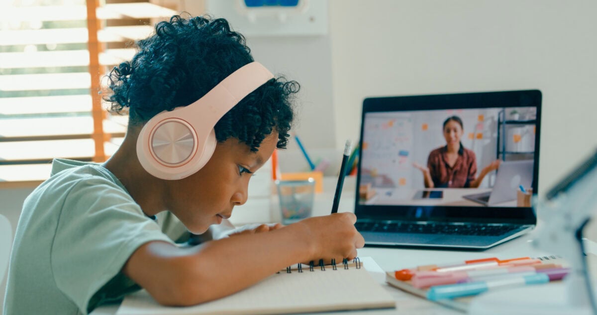 Young African American boy listens to teacher during remote learning session, demonstrating engagement through technology at home