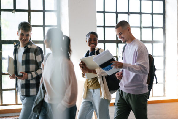 Group of Students Smiling and Talking Together in a Bright Hallway