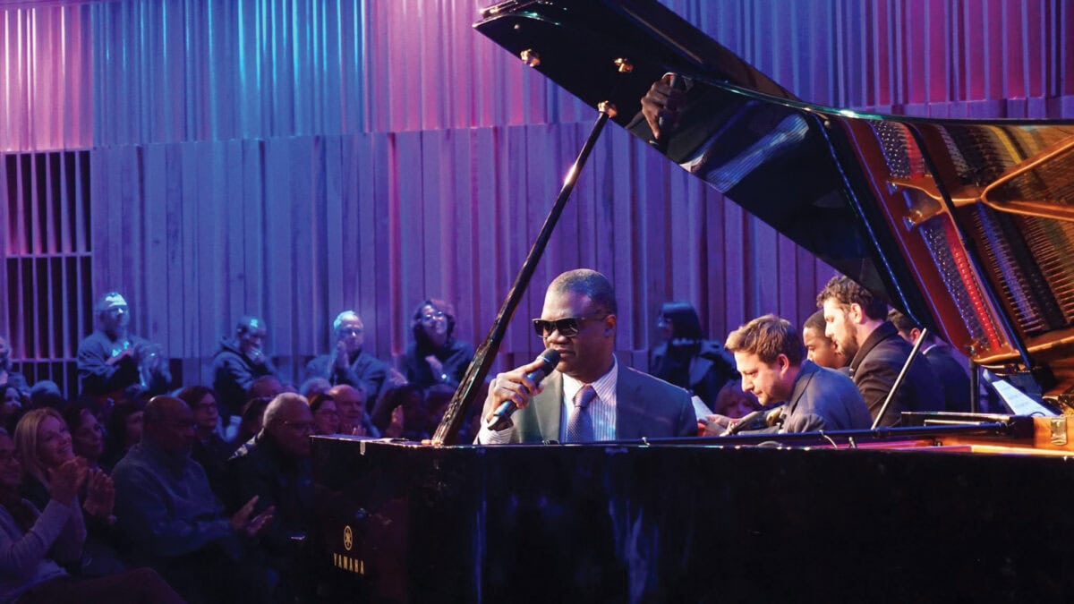 Marcus Roberts at the piano during a performance on stage with audience in background