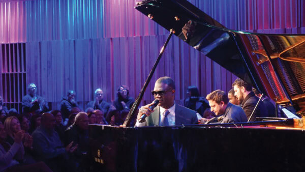 Marcus Roberts at the piano during a performance on stage with audience in background
