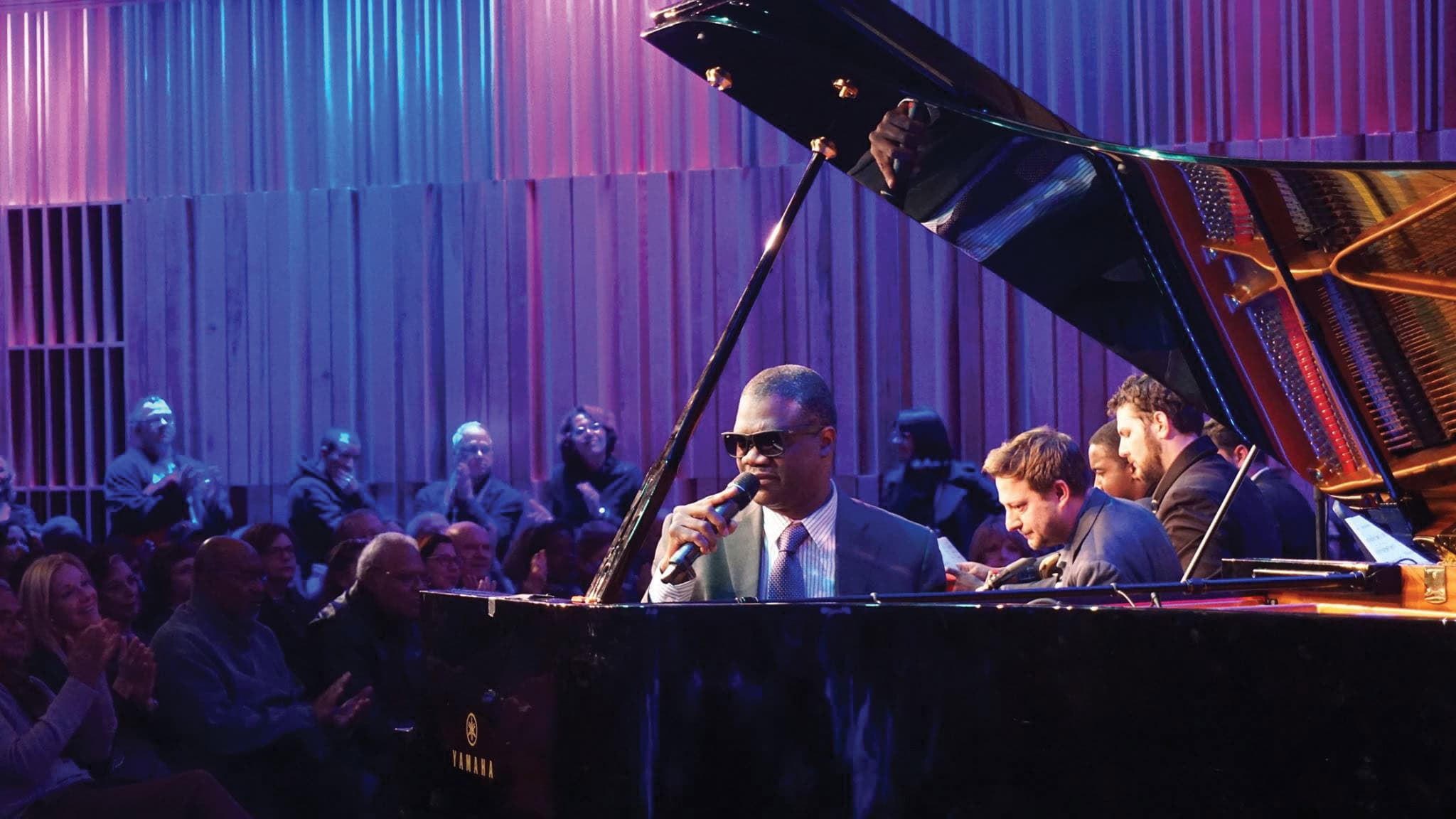 Marcus Roberts at the piano during a performance on stage with audience in background