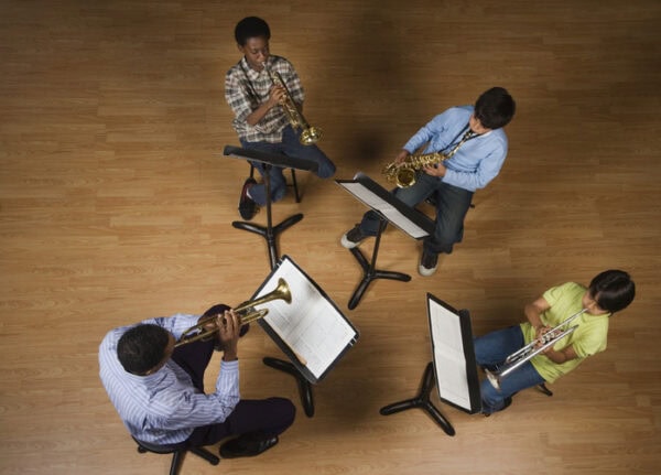 high school students learning to play trumpet and saxophone with teacher