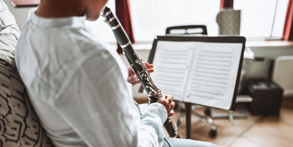 Boy learning scale exercises on clarinet from book