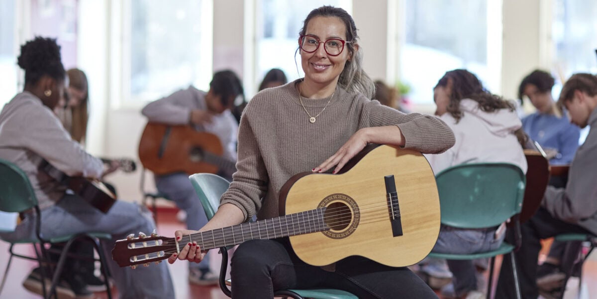 teacher during guitar class lesson with high school students