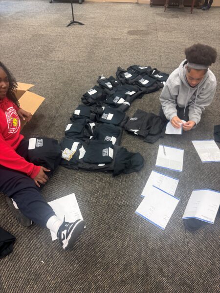 Tri-M students on floor organizing shirts and flyers